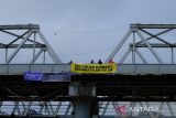Sejumlah relawan dari organisasi peduli lingkungan membentangkan spanduk berisi seruan penyelamatan lingkungan saat menggelar aksi di Jembatan Kapuas, Pontianak, Kalimantan Barat, Rabu (3/12/2025). Dalam aksi yang digelar para relawan dari Greenpeace, Tim Cegah Api, Gemawan, GMNI Kalbar, dan Extinction Rebellion Pontianak untuk memperingati Hari Relawan Sedunia tersebut mereka menyuarakan sejumlah isu, antara lain selamatkan bumi, penghentian pembakaran hutan dan lahan, pukul mundur krisis iklim, serta penyelamatan hutan dan ekosistem gambut. ANTARA FOTO/Jessica Wuysang