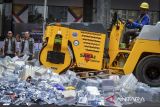 Direktur Jenderal Kekayaan Intelektual Kementerian Hukum Hermansyah Siregar (tengah) didampingi Direktur Penegakan Hukum Brigjen Pol Ari Ardian Rishadi (kiri) menyaksikan petugas menggunakan alat berat saat memusnahkan barang bukti hasil penindakan pelanggaran kekayaan intelektual di Jakarta, Selasa (9/12/2025). Direktorat Jenderal Kekayaan Intelektual (DJKI) Kementerian Hukum memusnahkan berbagai barang tiruan yang melanggar merek, desain industri, hak cipta dan paten dengan total estimasi kerugian senilai Rp3.072.100.000 sebagai bentuk komitmen pemerintah dalam melindungi ekosistem kekayaan intelektual. ANTARA FOTO/Putra M. Akbar/gp
