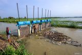 Warga membersihkan pintu air saluran irigasi dari sampah di sekitar persawahan terendam banjir di Kedungpring, Lamongan, Jawa Timur, Kamis (11/12/2025). Balai Besar Wilayah Sungai (BBWS) Bengawan Solo dan petani setempat bergotong royong mengendalikan banjir yang merendam ribuan lahan pertanian di wilayah itu dengan cara melakukan penyedotan air dan membersihkan saluran irigasi. Antara Jatim/Muhammad Mada/um 