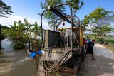 Petugas memeriksa pompa penyedot air di sekitar persawahan terendam banjir di Kedungpring, Lamongan, Jawa Timur, Kamis (11/12/2025). Balai Besar Wilayah Sungai (BBWS) Bengawan Solo dan petani setempat bergotong royong mengendalikan banjir yang merendam ribuan lahan pertanian di wilayah itu dengan cara melakukan penyedotan air dan membersihkan saluran irigasi. Antara Jatim/Muhammad Mada/um 