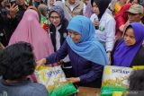 Gubernur Jawa Timur Khofifah Indar Parawansa (tengah) membagikan beras gratis saat gelaran pasar murah di Balai Desa Jarit, Candipuro, Lumajang, Jawa Timur, Jumat (12/12/2025). Pemerintah Provinsi Jawa Timur menggelar pasar murah yang telah berlangsung sebanyak 290 kali sebagai upaya pengendalian inflasi dan stabilisasi harga kebutuhan pokok menjelang perayaan Natal dan Tahun Baru 2026. ANTARA Jatim/Irfan Sumanjaya/mas.