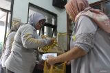 Petugas kelurahan memberikan minyak goreng pada warga penerima manfaat saat penyaluran Bantuan Pangan di Kantor Kelurahan Polehan, Malang, Jumat (12/12/2025). Penyaluran bantuan dari pemerintah pusat untuk periode OktoberNovember 2025 ini menyasar 20.932 warga penerima manfaat di Kota Malang, dengan setiap keluarga mendapatkan total 20 kg beras dan 4 liter minyak goreng guna meringankan beban pengeluaran rumah tangga serta menjaga ketahanan pangan dan membantu stabilitas harga kebutuhan pokok di pasar. ANTARA Jatim/Ari Bowo Sucipto/mas.