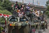 Prajurit TNI Angkatan Darat mendampingi warga menaiki kendaraan taktis (rantis) panser Anoa usai peringatan Hari Juang TNI AD di di Lapangan Manunggal Brigif 15/Kujang II, Kota Cimahi, Jawa Barat, Senin (15/12/2025). Demonstrasi militer dan parade serta pameran alat utama sistem senjata (alutsista) tersebut digelar dalam rangka memeriahkan peringatan Hari Juang TNI AD yang mengusung tema TNI AD manunggal dengan rakyat untuk Indonesia bersatu, berdaulat, sejahtera dan maju. ANTARA FOTO/Abdan Syakura/agr