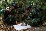 Personel Satgas Pamtas RI–Malaysia Yonarhanud 1/PBC/1 Kostrad dan personel Tentara Darat Malaysia (TDM) melihat peta perbatasan saat patroli bersama di hutan perbatasan Indonesia-Malaysia di Entikong, Kabupaten Sanggau, Kalimantan Barat, Selasa (25/11/2025). ANTARA FOTO/Jessica Wuysang