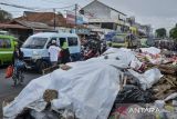 Warga berjalan di samping tumpukan sampah yang ditutupi terpal di Serpong, Tangerang Selatan, Banten, Selasa (16/12/2025). Pemerintah Kota Tangerang Selatan menutup tumpukan sampah menggunakan terpal sebagai bentuk penanganan sementara untuk mengurangi dampak bau selama masa penataan Tempat Pembuangan Akhir (TPA) Cipeucang yang membuat aktivitas pengangkutan sampah dihentikan sementara. ANTARA FOTO/Putra M. Akbar/gp