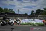 Pengendara motor melintas di samping tumpukan sampah yang ditutupi terpal di Ciater, Tangerang Selatan, Banten, Selasa (16/12/2025). Pemerintah Kota Tangerang Selatan menutup tumpukan sampah menggunakan terpal sebagai bentuk penanganan sementara untuk mengurangi dampak bau selama masa penataan Tempat Pembuangan Akhir (TPA) Cipeucang yang membuat aktivitas pengangkutan sampah dihentikan sementara. ANTARA FOTO/Putra M. Akbar/gp