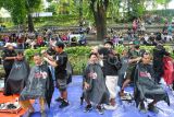 Sejumlah pemangkas rambut memotong rambut warga saat penggalangan dana di Taman Ekspresi, Kota Bogor, Jawa Barat, Sabtu (27/12/2025). Kegiatan konser musisi jalanan dan pangkas rambut dengan bayar seikhlasnya tersebut digelar untuk penggalangan dana bagi korban bencana alam di Aceh, Sumatera Barat dan Sumatera Utara. ANTARA FOTO/Arif Firmansyah/nz