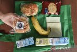 Siswa memperlihatkan menu Makan Bergizi Gratis (MBG) di SDN 1 Gunung Lipung, Kota Tasikmalaya, Jawa Barat, Senin (29/12/2025). Satuan Pelayanan Pemenuhan Gizi (SPPG) tetap menyalurkan bantuan MBG selama tiga hari berupa susu, buah, roti, biskuit, dan keju pada masa libur sekolah guna memastikan kebutuhan gizi anak tetap terpenuhi. ANTARA FOTO/Adeng Bustomi/agr