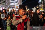 Anggota kepolisian berjaga di tengah kerumunan warga saat malam pergantian tahun di Braga, Bandung Jawa Barat, Rabu (31/12/2025). Sebanyak 880 personel polisi disiagakan untuk menjaga keamanan selama perayaan malam tahun baru di sejumlah lokasi wisata di Kota Bandung yang menerapkan pelarangan menyalakan kembang api oleh Pemerintah Kota Bandung. ANTARA FOTO/Novrian Arbi/agr