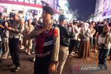Anggota kepolisian berjaga di tengah kerumunan warga saat malam pergantian tahun di Braga, Bandung Jawa Barat, Rabu (31/12/2025). Sebanyak 880 personel polisi disiagakan untuk menjaga keamanan selama perayaan malam tahun baru di sejumlah lokasi wisata di Kota Bandung yang menerapkan pelarangan menyalakan kembang api oleh Pemerintah Kota Bandung. ANTARA FOTO/Novrian Arbi/agr