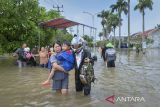 Warga menggendong anaknya melintasi jalan yang terendam banjir di Perumahan Duta Bandara Permai, Kosambi, Kabupaten Tangerang, Banten, Senin (12/1/2026). Badan Penanggulangan Bencana Daerah (BPBD) Kabupaten Tangerang mencatat sebanyak enam wilayah kecamatan terdampak banjir dengan ketinggian mulai dari 30-140 sentimeter yang berdampak terhadap sekitar 1.014 kepala keluarga. ANTARA FOTO/Putra M. Akbar/gp