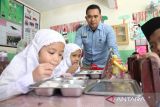 Kepala Satuan Pelayanan Pemenuhan Gizi (SPPG) Polrestabes Medan Adi Teguh Santoso (kiri) menyaksikan siswa menyantap makanan bergizi gratis saat   pelaksanaan program Makan Bergizi Gratis di Sekolah Madrasah Ibtidaiyah Negeri Medan, Sumatera Utara, Rabu (14/1/2026). Pemantau tersebut guna memastikan kualitas dan keamanan pangan yang di santap siswa. ANTARA/Yudi Manar