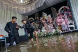Pengantin wanita bersama keluarga bersiap melakukan pemotretan di lokasi resepsi yang tergenang banjir di Desa Pacar, Tirto, Kabupaten Pekalongan, Jawa Tengah, Minggu (18/1/2026). Pasangan pengantin itu tetap melangsungkan resepsi pernikahan meskipun banjir rmenggenangi lokasi acara di sekitar rumah mempelai sejak Jumat (16/1) akibat tingginya curah hujan di Pekalongan. ANTARA FOTO/Harviyan Perdana Putra/rwa.