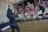 Pasangan pengantin bersama keluarga melakukan sesi foto di tengah lokasi resepsi yang terdampak banjir, di Desa Pacar, Tirto, Kabupaten Pekalongan, Jawa Tengah, Minggu (18/1/2026). Pasangan pengantin itu tetap melangsungkan resepsi pernikahan meskipun banjir rmenggenangi lokasi acara di sekitar rumah mempelai sejak Jumat (16/1) akibat tingginya curah hujan di Pekalongan. ANTARA FOTO/Harviyan Perdana Putra/rwa.