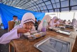 Sejumlah siswa menikmati makanan bergizi gratis (MBG) di bawah tenda darurat SDN 05 Kayu Pasak, Nagari Salareh Aia, Palembayan, Agam, Sumatera Barat, Jumat (23/1/2026). MBG mulai dibagikan untuk 97 siswa di sekolah terdampak bencana itu sejak Senin (19/1/2026). ANTARA FOTO/Iggoy el Fitra/foc.