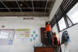 Petugas merapikan kabel listrik yang menjuntai akibat plafon salah satu ruang kelas runtuh di SMP Negeri 60, Surabaya, Jawa Timur, Rabu (28/1/2026). Sebagian plafon di ruang kelas yang berada di lantai 3 itu runtuh saat berlangsungnya proses belajar dan pihak sekolah dan Badan Penanggulangan Bencana Daerah (BPBD) Kota Surabaya memindahkan pelajar-pelajar di lantai 3 untuk sementara melakukan proses kegiatan belajar mengajar di lantai 2, lantai 1 maupun di halaman sekolah. ANTARA Jatim/Didik Suhartono/mas.