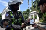 Personel Sat Lantas Polresta Bogor Kota menyerahkan bukti struk yang tercetak kepada pelanggar lalu lintas yang tidak menggunakan helm di depan Tugu Kujang, Kota Bogor, Jawa Barat, Rabu (11/2/2026). Penggunaan alat tilang Electronic Traffic Law Enforcement (ETLE) Mobile tersebut untuk memudahkan dan menindak pelanggaran secara langsung selama Operasi Keselamatan Lodaya 2026 yang mendeteksi pelanggaran lalu lintas seperti parkir sembarangan, pelanggaran rambu dan tidak menggunakan helm dengan bukti struk yang tercetak. ANTARA FOTO/Arif Firmansyah/foc. 