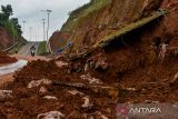 Warga melintasi jalan yang longsor di Jalur Lingkar Utara Jatigede, Kabupaten Sumedang, Jawa Barat, Jumat (13/2/2026). Longsor di Jalur Lingkar Utara Jatigede akibat hujan deras yang mengguyur Kabupaten Sumedang pada Kamis (12/2) tersebut membuat jalur yang menghubungkan Kabupaten Sumedang dan Kabupaten Majalengka ditutup sementara karena dapat membahayakan pengendara. ANTARA FOTO/Raisan Al Farisi/agr