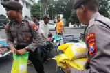 Polisi membawa beras SPHP untuk dibagikan kepada tukang becak di Jalan Pahlawan, Surabaya, Jawa Timur, Jumat (13/2/2026). Kepolisian setempat membagikan beras, gula, dan minyak goreng secara gratis kepada seribu tukang becak di Kota Surabaya sebagai bentuk kepedulian sosial serta dukungan terhadap program stabilisasi harga dan ketahanan pangan guna membantu meringankan beban ekonomi warga berpenghasilan rendah. ANTARA Jatim/Didik Suhartono/abs