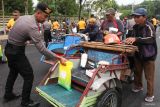 Polisi memberi beras SPHP kepada tukang becak di Jalan Pahlawan, Surabaya, Jawa Timur, Jumat (13/2/2026). Kepolisian setempat membagikan beras, gula, dan minyak goreng secara gratis kepada seribu tukang becak di Kota Surabaya sebagai bentuk kepedulian sosial serta dukungan terhadap program stabilisasi harga dan ketahanan pangan guna membantu meringankan beban ekonomi warga berpenghasilan rendah. ANTARA Jatim/Didik Suhartono/abs