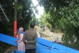 Warga mengamati jembatan gantung Darus atau Jembatan Cinta rusak akibat banjir di Desa Jubung, Sukorambi, Jember, Jawa Timur, Sabtu (14/2/2026). Jembatan  penghubung Kecamatan Sukorambi dan Ajung tersebut terputus akibat banjir pada Kamis (12/2) mengakibatkan warga harus menggunakan rute lain sejauh tujuh kilometer dari sebelumnya satu kilometer. Antara Jatim/Seno/abs