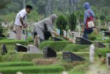 Warga membersihkan makam keluarganya saat ziarah di Tempat Pemakaman Umum (TPU) Keputih, Surabaya, Jawa Timur, Senin (16/2/2026). Menjelang bulan suci Ramadhan, umat Islam melakukan ziarah kubur untuk mendoakan sanak keluarga dan kerabat yang sudah meninggal. ANTARA Jatim/Didik Suhartono/mas.