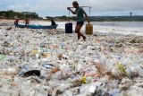 Nelayan mengangkut air melewati tumpukan sampah kiriman di Pantai Kedonganan, Badung, Bali, Kamis (26/2/2026). Menurut nelayan setempat, sejak Rabu (25/2) sampah kiriman yang didominasi sampah plastik tersebut menumpuk di objek wisata itu menyusul tingginya gelombang laut disertai angin kencang. 
