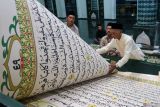 Petugas membalik lembar halaman Al Quran raksasa di Masjid Agung Baiturrahman, Banyuwangi, Jawa Timur, Minggu (1/3/2026). Al Quran berukuran 142 x 210 sentimeter yang ditulis tangan oleh Abdul  Karim pada 2010 itu dibutuhkan dua orang untuk membalik halaman dan dibaca bergantian setiap bulan Ramadhan. ANTARA Jatim/Budi Candra Setya/mas.
