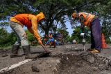 Pekerja memperbaiki jalan di ruas jalan nasional Nganjuk, Jawa Timur, Senin (9/3/2026). Balai Besar Pelaksanaan Jalan Nasional (BBPJN) Jawa Timur - Bali melakukan perbaikan jalan nasional di Jawa Timur dengan pengaspalan dan pengecoran di sekitar 14.132 titik lubang yang terdata sepanjang 2.261,68 kilometer yang ditargetkan rampung pada H-10 Lebaran guna memberikan keamanan dan kenyamanan bagi pengendara saat arus mudik Idul Fitri 1447 H. ANTARA Jatim/Muhammad Mada/mas.