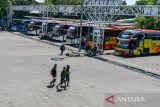 Warga berjalan di depan bus di Terminal Leuwipanjang, Bandung, Jawa Barat, Jumat (13/3/2026). Pengelola Terminal Leuwipanjang mencatat bahwa tiket mudik lebaran 2026 telah terjual hingga 70 persen dengan tujuan favorit yaitu Jawa Tengah, Jawa Timur dan Bali. ANTARA FOTO/Raisan Al Farisi/agr