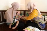 Bidan desa Fidya Mirza (kanan) menyuntikkan vaksin measles-rubella (MR) kepada seorang anak dalam kegiatan jemput bola imunisasi campak di rumah warga di Kelurahan Karangbesuki, Kota Malang, Jawa Timur, Kamis (2/4/2026). Kegiatan tersebut merupakan bagian dari pelaksanaan Catch Up Campaign (CUC) campak yang menyasar sekitar 13 ribu anak usia 9 bulan hingga 13 tahun untuk meningkatkan cakupan imunisasi, mencegah penyebaran penyakit, serta mencapai kekebalan kelompok (herd immunity) sebesar 95 persen, menyusul temuan sedikitnya 17 kasus campak pada awal 2026 di Kota Malang. Antara Jatim/Ari Bowo Sucipto