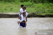 SISWA DAN GURU MENYEBERANGI SUNGAI UNTUK BELAJAR MENGAJAR