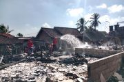 Petugas membersihkan material sisa kebakaran rumah adat Sade Lombok