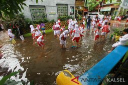 Murid SD bermain air hujan