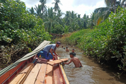 Kelotok tak bisa masuk, material bangunan terpaksa diangkut melewati anak sungai