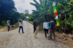 Warga dan TNI bergotong royong mengangkut Sertu untuk perbaiki jalan
