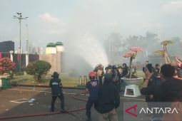 Massa lempari polisi dengan batu saat petugas coba padamkan api  di depan gedung DPR RI