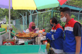 Pekerja muda Pertamina bagi  bahan makanan ke pedagang asongan