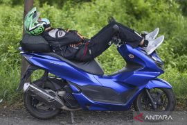 Pemudik bersepeda motor istirahat tidur di tepi Jalan Pantura