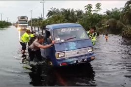 Anggota Polres Pelalawan bantu pengendara lewati banjir sambil serukan pemilu damai