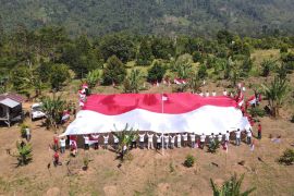 Polisi dan eks napiter membentangkan bendera Merah Putih di Gunung Poso
