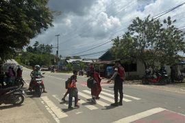 Personel Ditsamapta Polda Kaltara Bantu Anak Sekolah Menyeberang Jalan