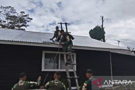 Prajurit TNI Satgas Yonif 511 memperbaiki lampu tenaga surya Gereja Popome