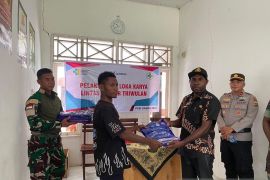 Prajurit TNI Satgas Yonif 511/DY membagikan kelambu kepada warga Papua