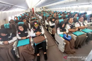 Petugas haji salat berjamaah di dalam pesawat
