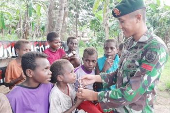 Prajurit TNI mengajak anak-anak Kampung Kondo minum susu