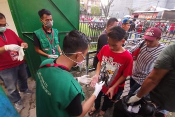 Relawan  semprotkan  antiseptik ke tangan Penonton PSM vs Barito