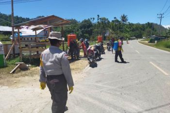 Warga Holtekamp semprotkan cairan disinfektan terhadap kendaraan
