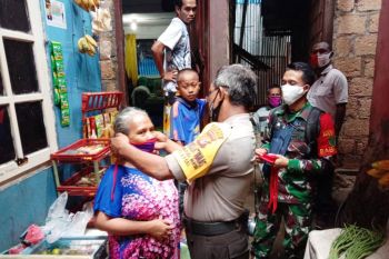 Polri dan TNI di Kelurahan Numbay bagi masker gratis ke warga