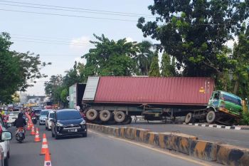 Truk peti kemas terguling di tengah jalan